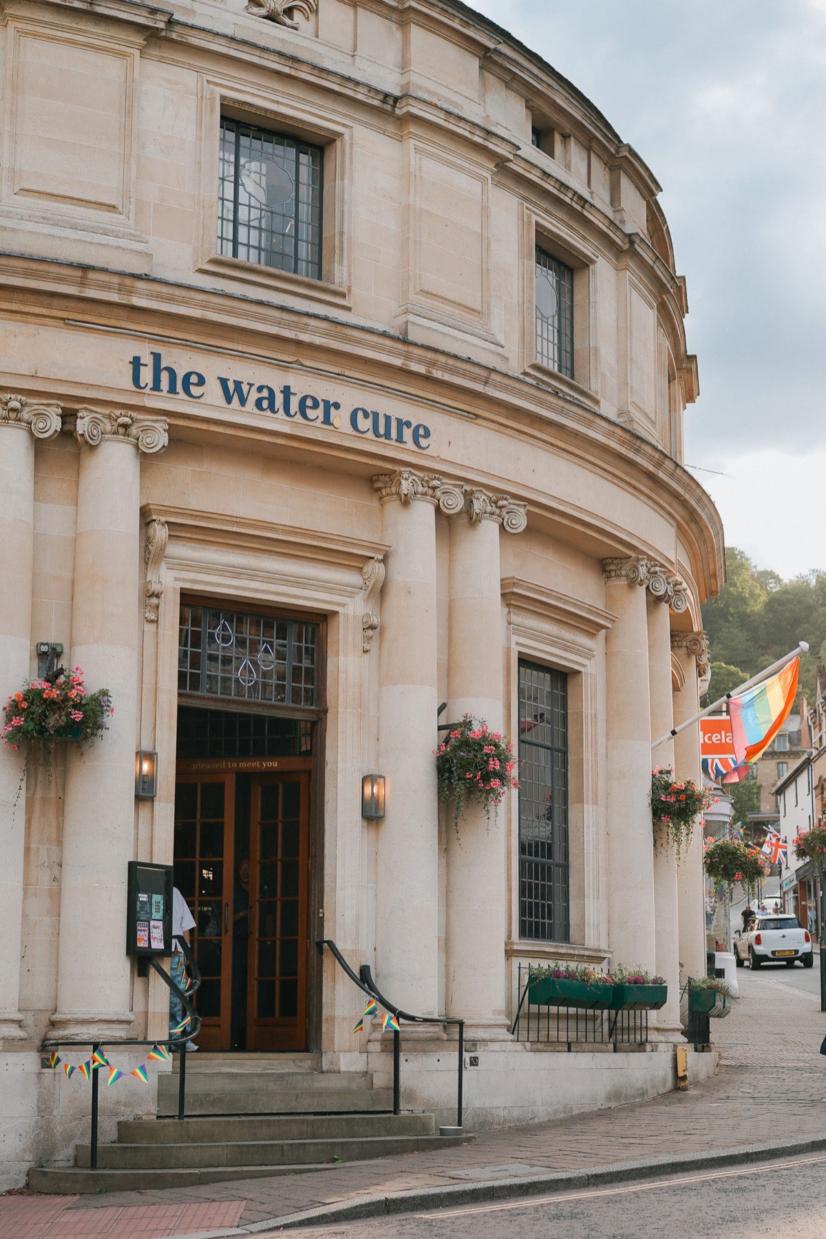 The curved stone frontage of The Water Cure on a hill street in Malvern