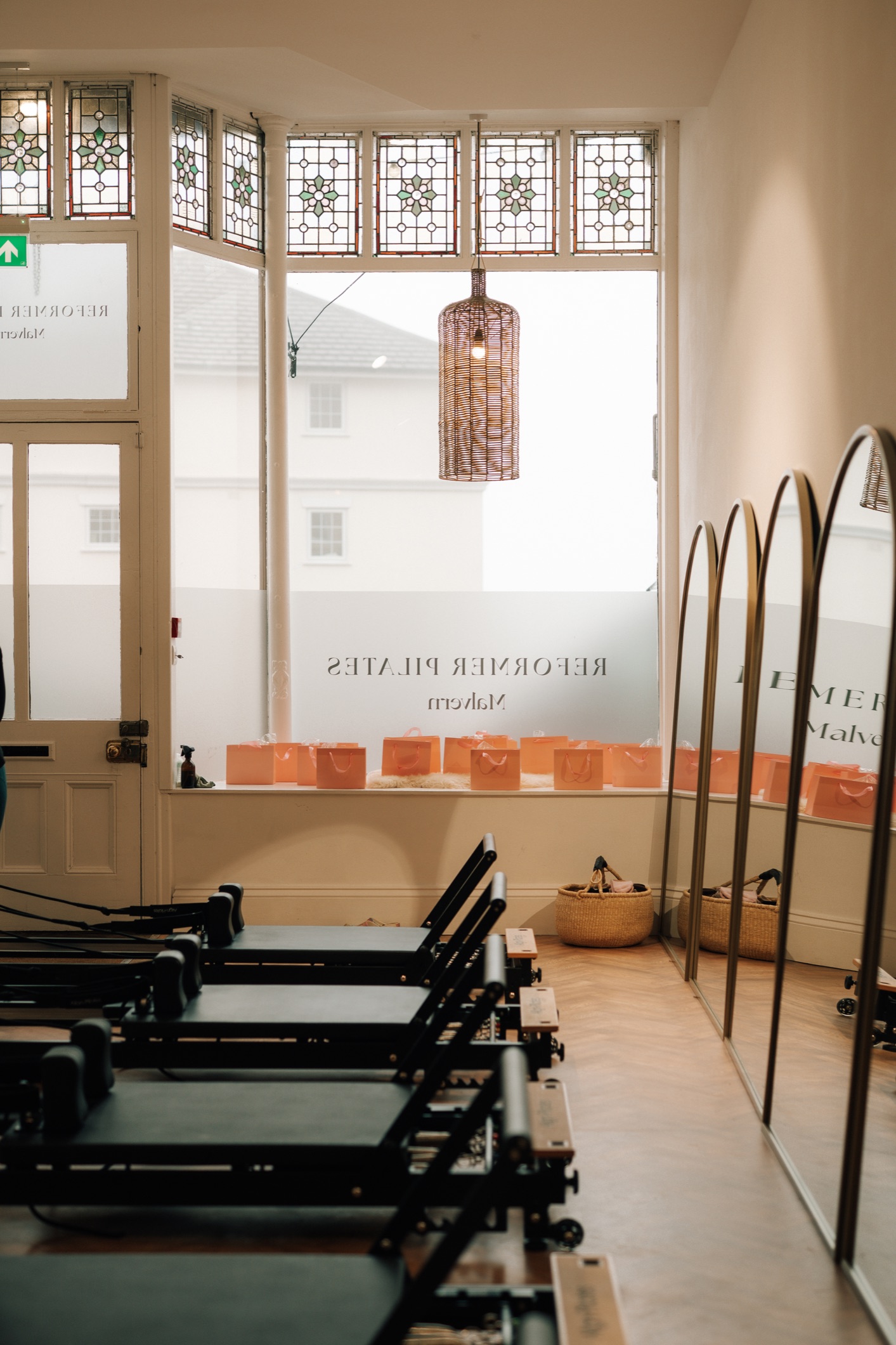 Reformer beds lined up beneath a stained glass shopfront window at Reformer Pilates Malvern